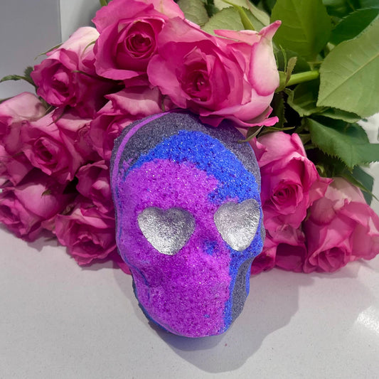 Pink purple and black swirled skull shaped bath bomb surrounded by pink roses.